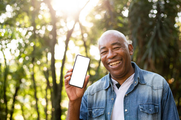Middle-aged man smiling and using cell phone device screen stock photo