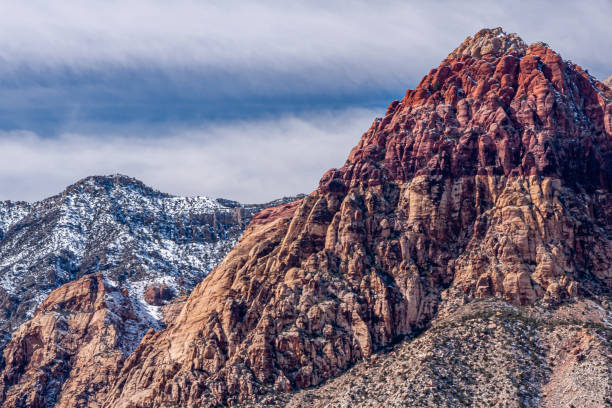Las Vegas, Nevada, USA - February 23, 2010: Red Rock Canyon Conservation Area. One snow covered and the other red stone mountain peaks against blue cloudscape.