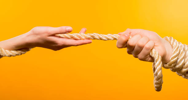istock two hands in different positions are tied with a white wide rope on a yellow background close-up 1388269708