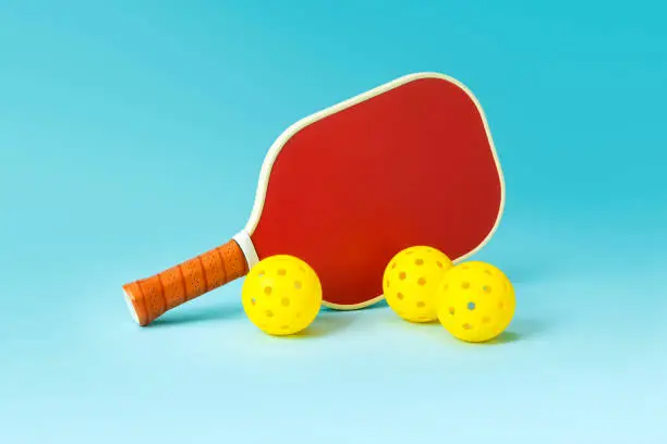 Photo of Red Pickleball Paddle and Yellow Ball on Blue Background