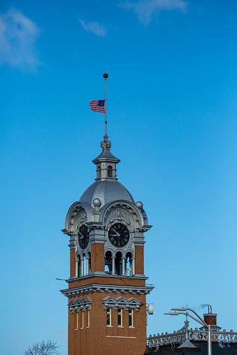 Flag flying at half-staff on top of the clock tower that is on top of lincoln county circuit court house in merrill, Wisconsin