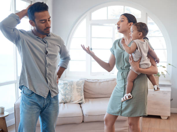 photo d’un jeune couple l’air frustré et se disputant dans le salon à la maison - husband wife family ethnic photos et images de collection