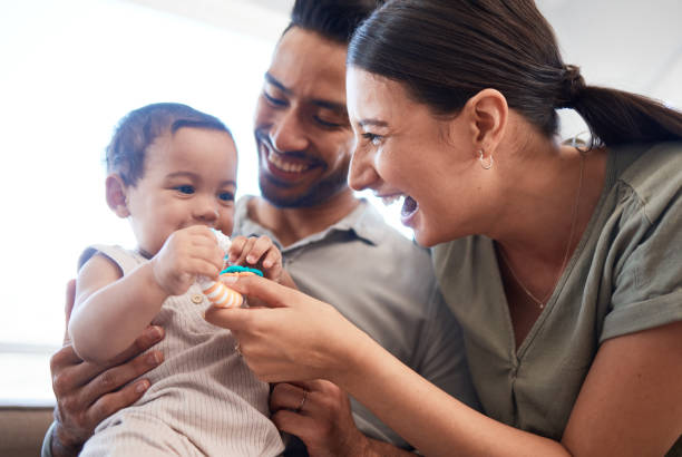 zdjęcie młodej pary wiążącej się ze swoją córeczką na sofie w domu - babies and children zdjęcia i obrazy z banku zdjęć