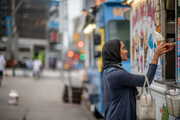Photo of Muslim Woman Buying Ice Cream Downtown