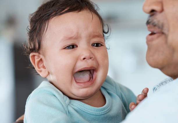 aufnahme eines unkenntlichen mannes, der sein weinendes enkelkind zu hause hält - babies only audio stock-fotos und bilder