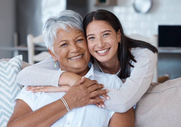 shot of a young woman bonding with her mother on a sofa at home - senior adult imagens e fotografias de stock