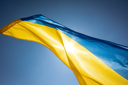 National flag of Ukraine waving outside on a wind facing the bright sky and the Sun