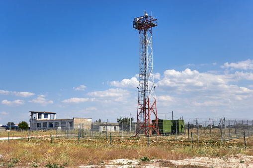 A working red-and-white base station for Internet and mobile communications. A tall tower standing in a field.