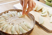 Cooking an apple pie. Putting the sliced apples into a  pastry mould with dough.