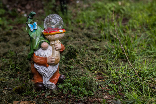 Two garden gnomes sit on a stone and play chess