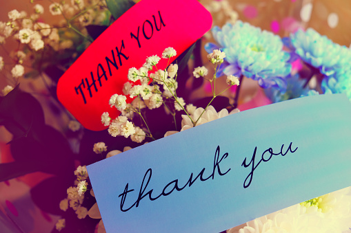 A bouquet of brightly coloured flowers with a cards saying thank you.