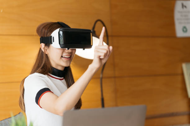 istock Woman wearing virtual reality goggles standing in a office. VR glasses. 360 degrees. Virtual reality headset. VR game. Wearing virtual reality goggles. Smartphone with VR. Virtual reality video. 1388296468