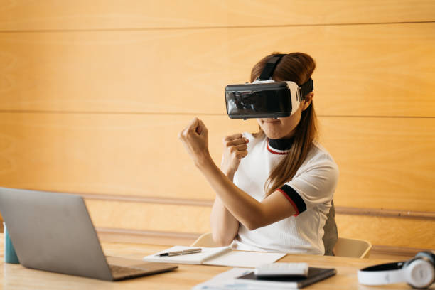 istock Woman wearing virtual reality goggles standing in a office. VR glasses. 360 degrees. Virtual reality headset. VR game. Wearing virtual reality goggles. Smartphone with VR. Virtual reality video. 1388296511