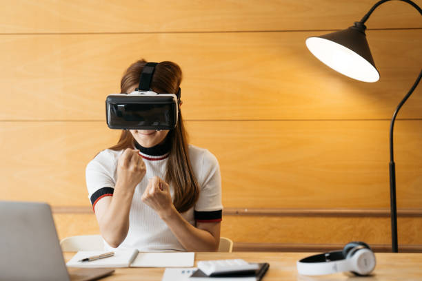 istock Woman wearing virtual reality goggles standing in a office. VR glasses. 360 degrees. Virtual reality headset. VR game. Wearing virtual reality goggles. Smartphone with VR. Virtual reality video. 1388296513