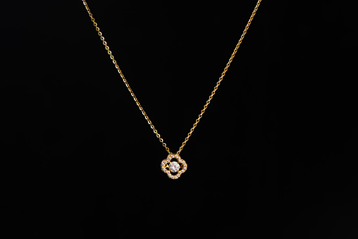 golden pendant with chain on black background