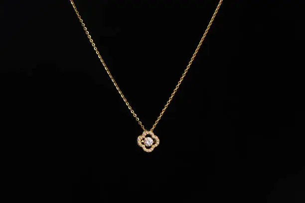 Photo of golden pendant with chain on black background