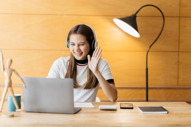 istock Smiling Asian young female using headset looking at laptop screen listen and learning online courses. Happy chinese business woman with headphones video call for customer service 1388297250