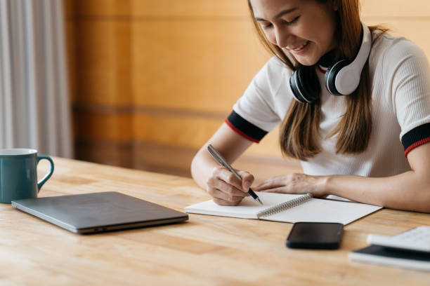 istock Happy asian in headphone use laptop take online course training make notes. Smiling young Asian female student in earphones study on computer from home. Distance education concept. 1388297376