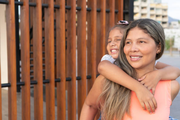 istock Mother carrying her daughter on piggyback. 1388298321