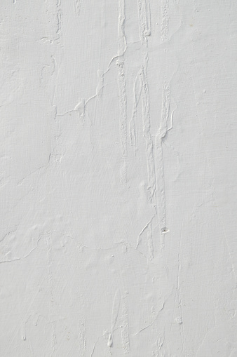 Plain white gray grunge blotched smudged plastered wall like vertical backgrounds. Apt to use as wallpaper, background, post cards, letters, manuscripts, historical ancient backdrops. There are lines of water trickling down and mud spots.