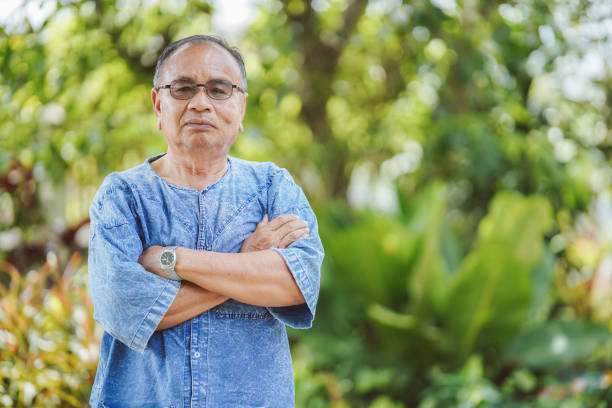 istock An elderly Thai man standing with his arms crossed looking at the camera with a blurred natural background. Copy space. 1388299697