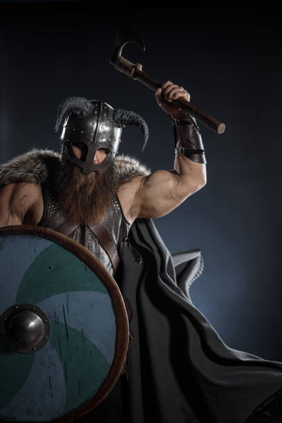 istock Medieval warrior berserk Viking in armor and helmet with horns with axes attacks enemy. Concept historical photo of Scandinavian god 1388302410