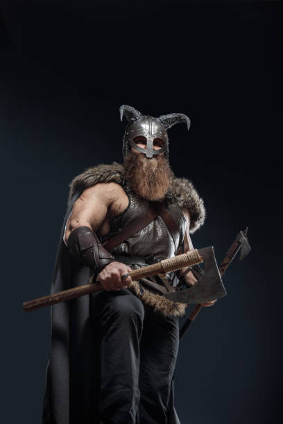 istock Medieval warrior berserk Viking in armor and helmet with horns with axes attacks enemy. Concept historical photo of Scandinavian god 1388302519