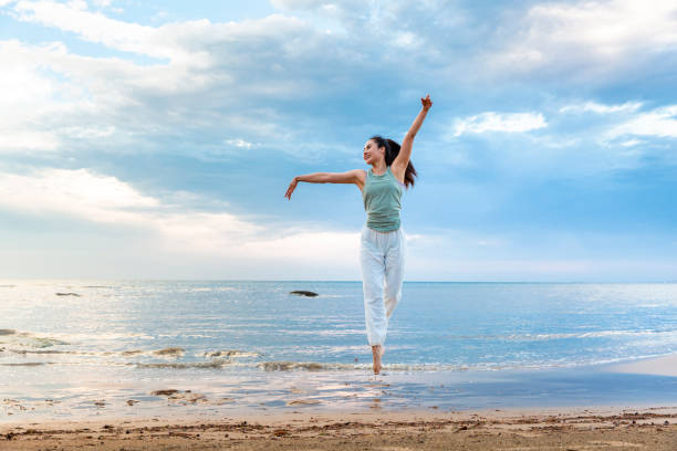 junge frau, die alleine yoga an einem sommerstrand praktiziert - stockfoto - wading stock-fotos und bilder