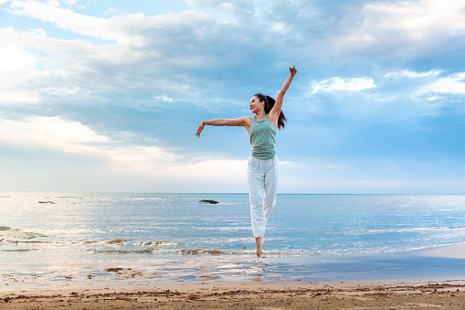 Young woman practicing yoga alone on a summer beach - stock photo