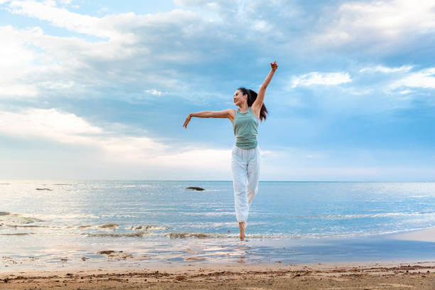 Young woman practicing yoga alone on a summer beach - stock photo Young woman practicing yoga alone on a summer beach - stock photo people jumping sea beach stock pictures, royalty-free photos & images