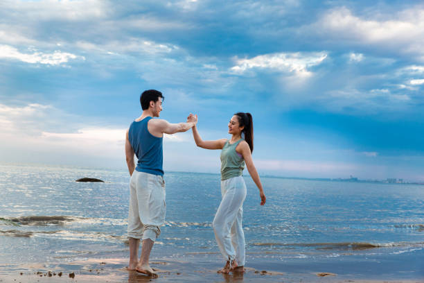 istock Trainer and student who complete a challenge celebrate by high-fiving under magnificent seaside clouds - stock photo 1388304243