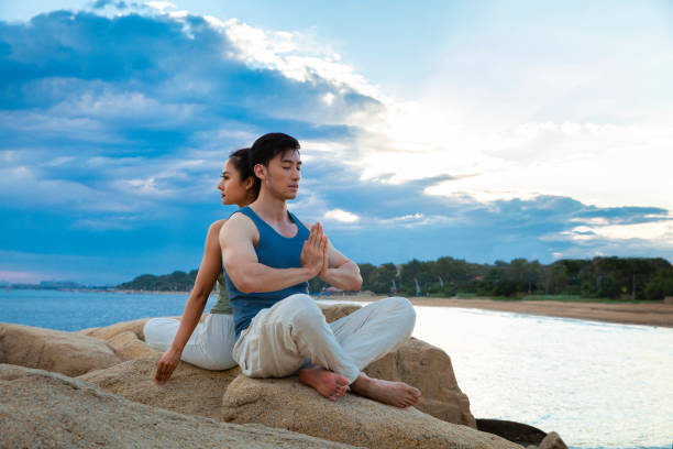 istock Couples practicing yoga mindfulness on island rocks - stock photo 1388304244
