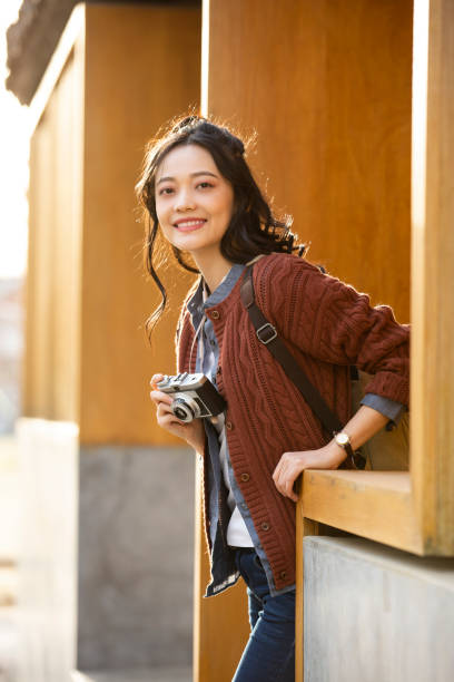 Female tourist with a camera - stock photo A female tourist holding a camera is walking out of the gate of the scenic spot. Portrait. center athlete stock pictures, royalty-free photos & images