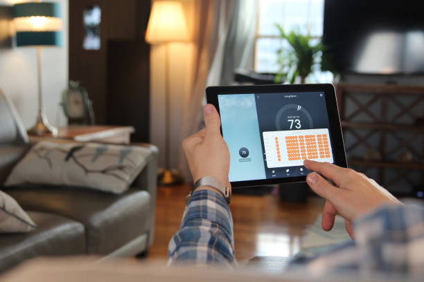 Man is Adjusting a temperature using a tablet with smart home app stock photo