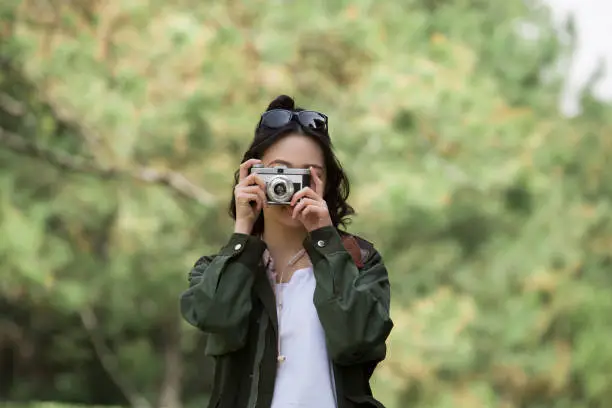 Photo of Female tourist taking photos by pine forest - stock photo