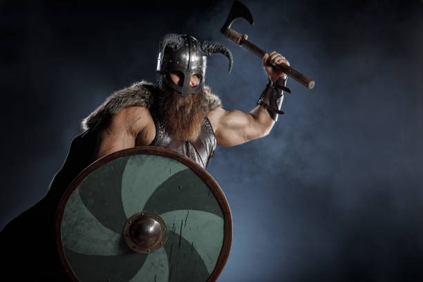 istock Medieval warrior berserk Viking in armor and helmet with horns with axes attacks enemy. Concept historical photo of Scandinavian god 1388305743