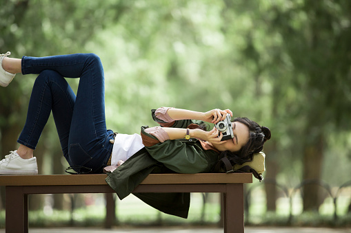 Young female tourist is lying on a forest park bench for a photo shoot. Portrait.