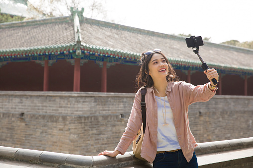 Young female tourist taking a selfie beside an ancient Chinese corridors - stock photo