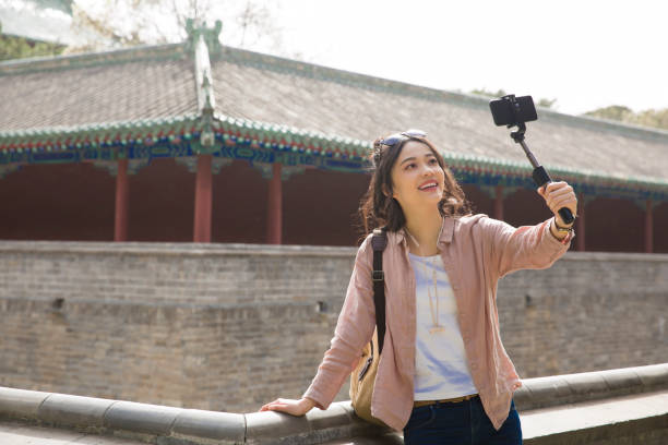 Young female tourist taking a selfie beside an ancient Chinese corridors - stock photo stock photo