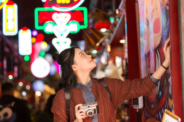 joven estudiante universitaria admirando cartel de arte en un mercado nocturno en beijing - foto de archivo - hair bun asian ethnicity profile women fotografías e imágenes de stock