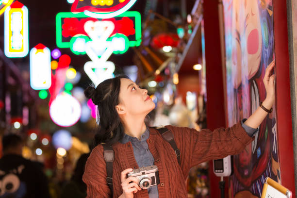 young female college student admiring art poster at a night market in beijing - stock photo - hair bun asian ethnicity profile women imagens e fotografias de stock