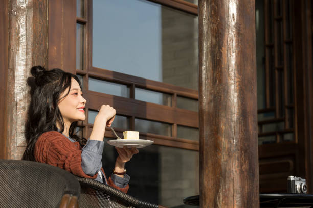 chinese college student enjoying afternoon tea in sidewalk cafe - stock photo - hair bun asian ethnicity profile women imagens e fotografias de stock