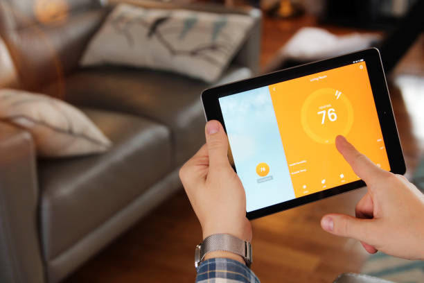 istock Man is Adjusting a temperature using a tablet with smart home app in modern living room. 1388307271