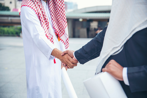 Arab Businessman Muslim dress shaking hands together. Muslim Men Teamwork business partner handshake with business Partnership. Close up hand UAE diversity multiracial people trust honesty commitment