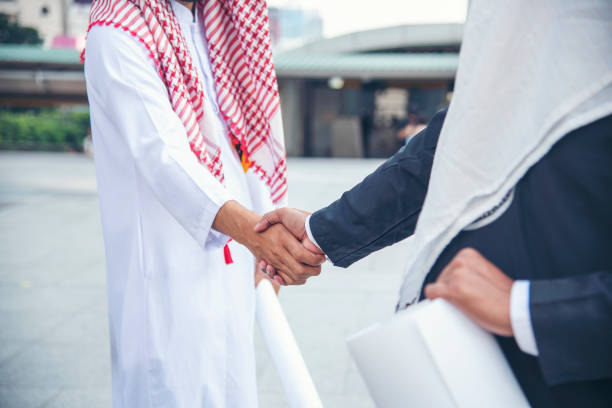 arabski biznesmen muzułmański strój ściskający dłonie. muslim men teamwork partner biznesowy uścisk dłoni z partnerstwem biznesowym. z bliska różnorodność zea wielorasowi ludzie ufają uczciwości zaangażowanie - sheik abu dhabi united arab emirates asia zdjęcia i obrazy z banku zdjęć