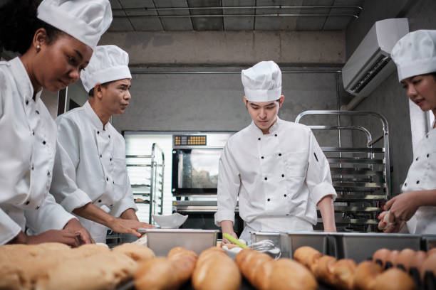 istock Chefs team in uniforms prepare to bake bread and pastry in stainless kitchen. 1388307891