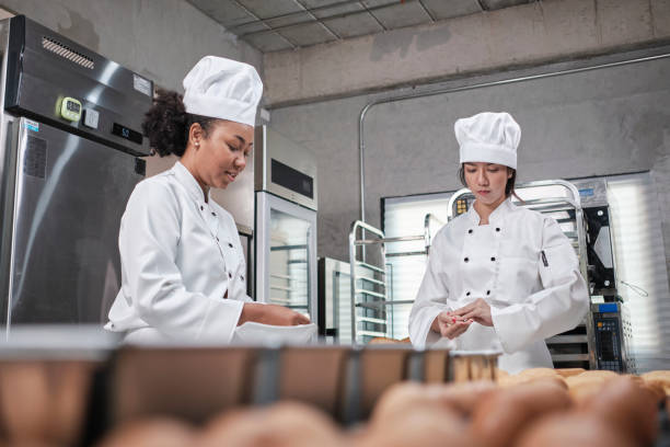 istock Female chefs in uniforms prepare to bake bread and pastry in stainless kitchen. 1388307922