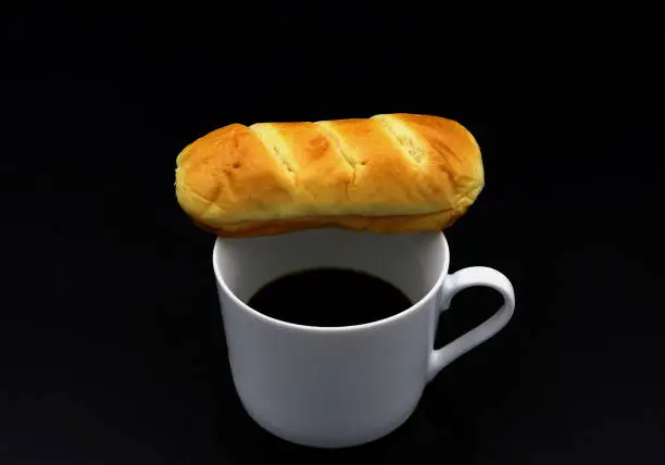 Butterbread next to a cup of coffee with a black background