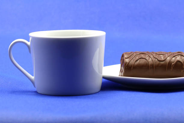 Breakfast cup next to a white plate with a piece of chocolate cake
