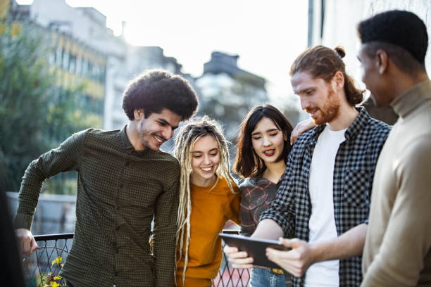 istock Group of happy friends using touchpad on a terrace. 1388311724